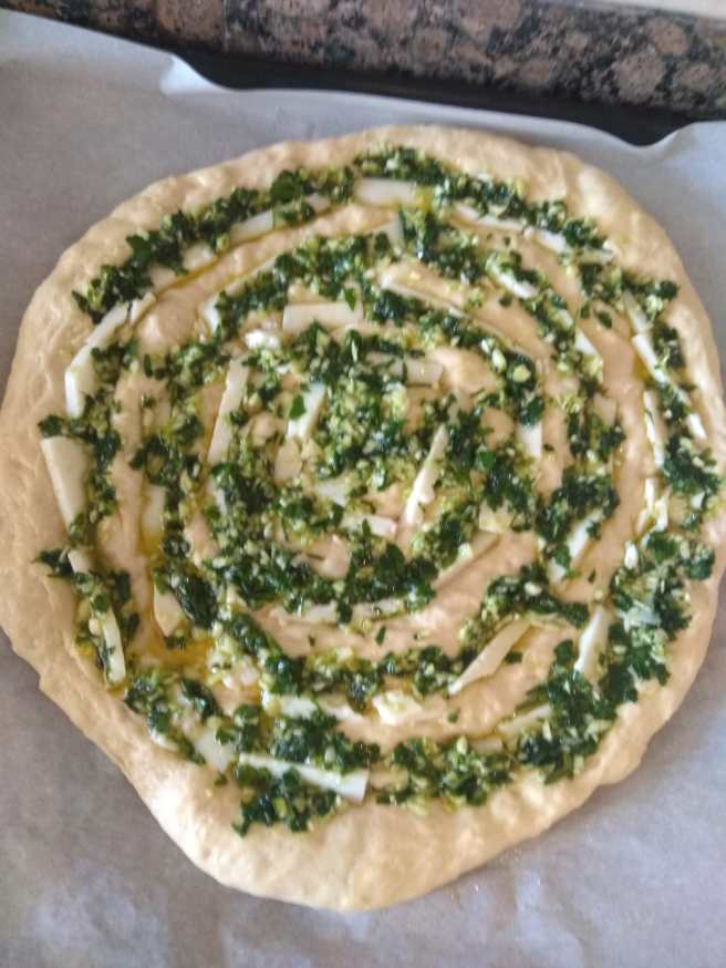 Coca amb mozarella, all i julivert, muntada pendent de fermentar